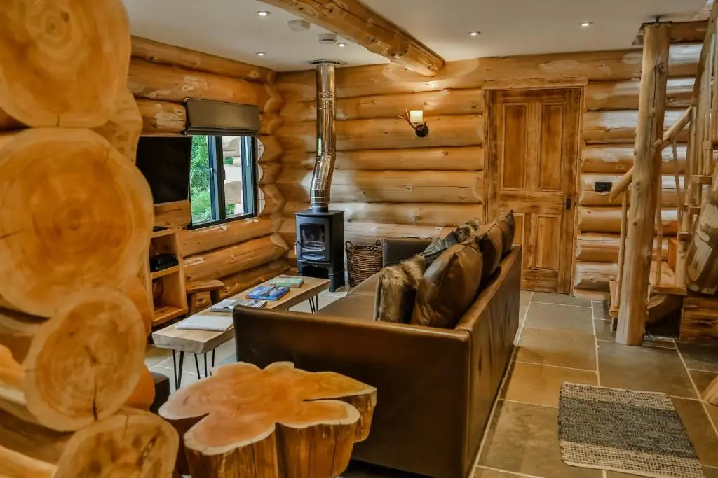 a log cabin living room with a couch and a stove at Cedar Lodge in Aviemore