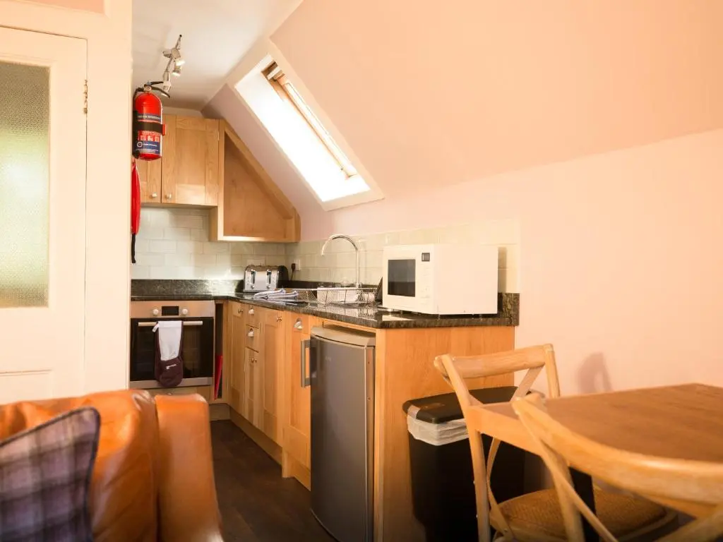 a kitchen with wooden cabinets and a table in it at Ptarmigan in Aviemore