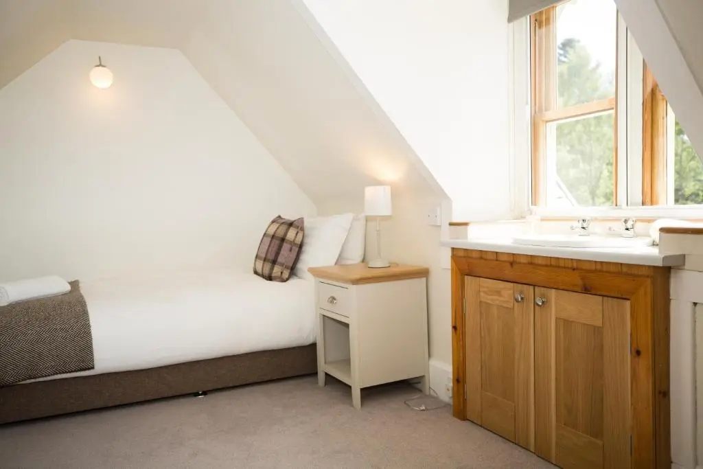 a bedroom with a bed and a sink and a window at Ptarmigan in Aviemore