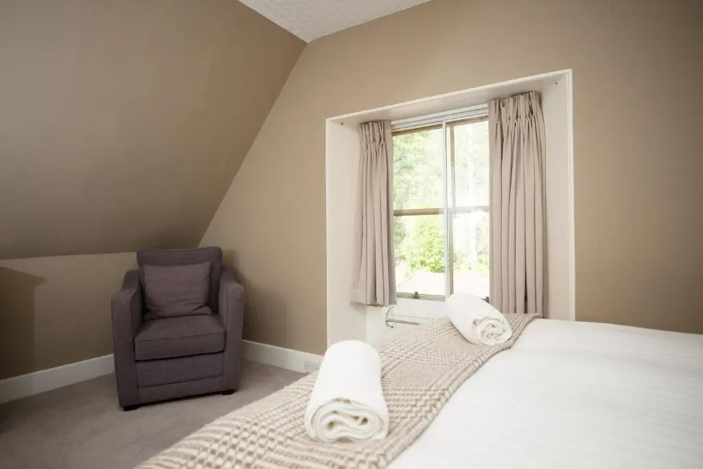a bedroom with a bed and a chair and a window at Ptarmigan in Aviemore