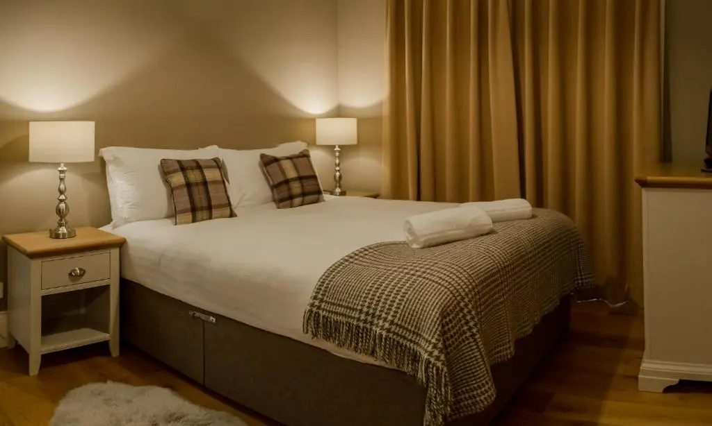a bedroom with a large bed with white sheets and pillows at Shieling in Aviemore