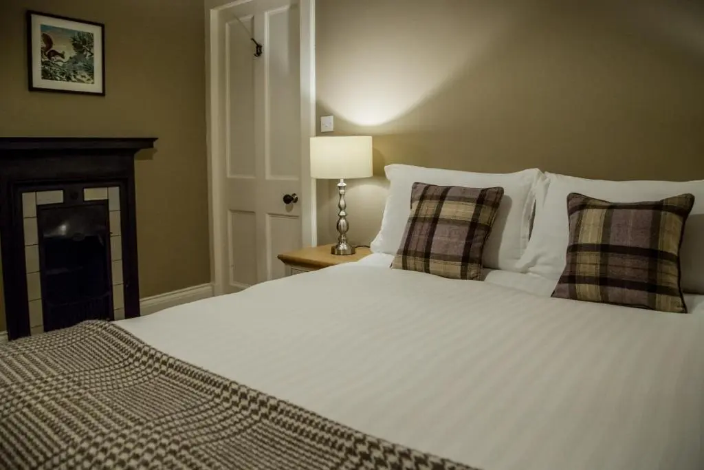 a bedroom with a large white bed with a fireplace at Shieling in Aviemore