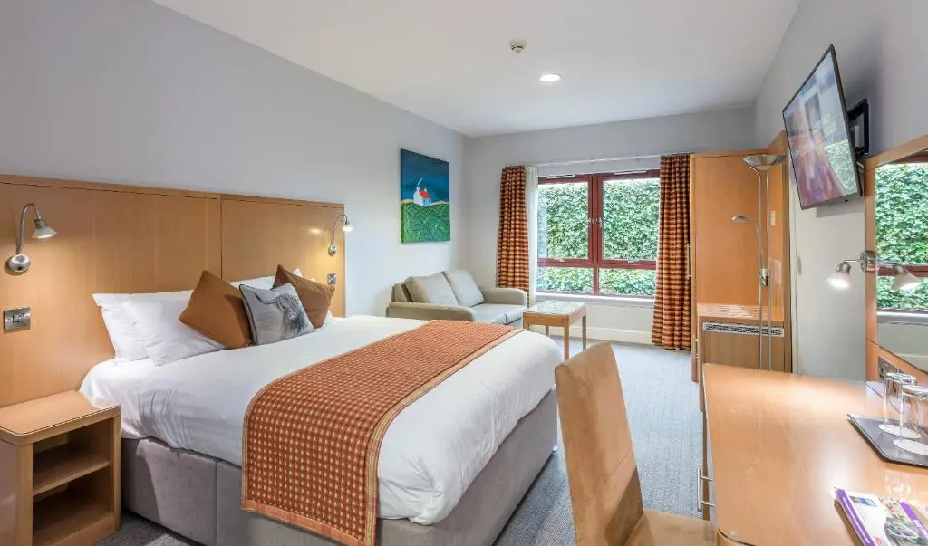 a hotel room with a large bed and a desk at High Range Lodge Hotel in Aviemore
