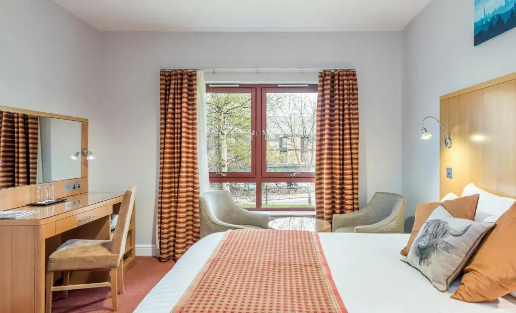 a bedroom with a bed and a desk and a window at High Range Lodge Hotel in Aviemore