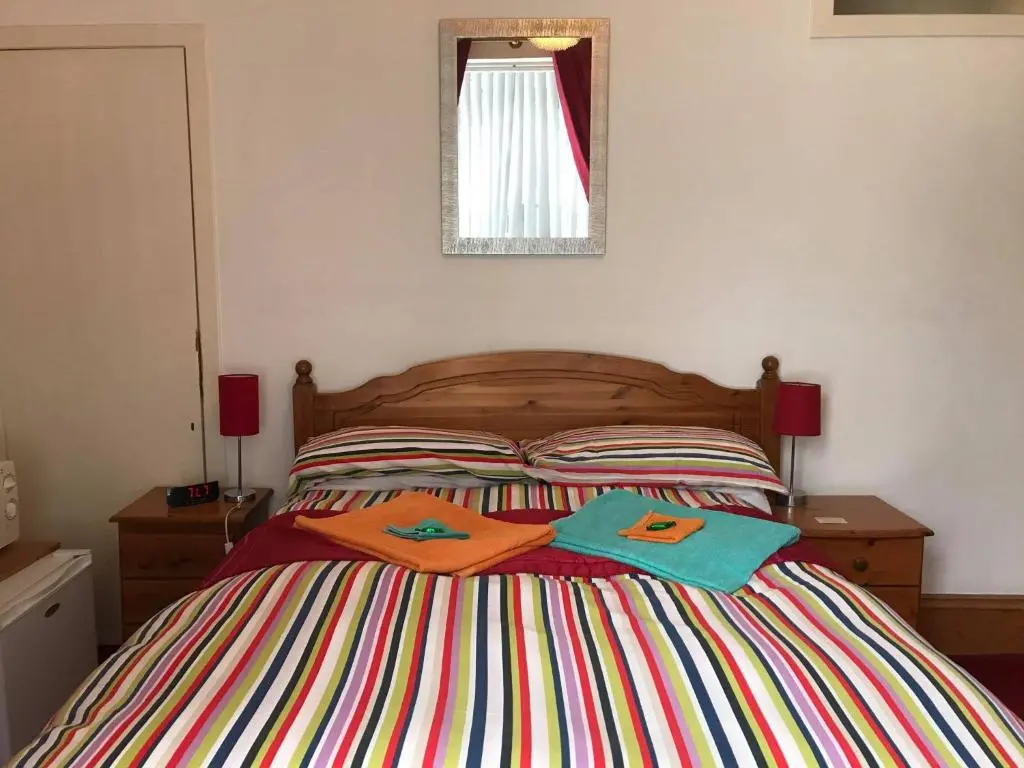 a bedroom with a bed with two towels on it at Broomlea Guest House in Dyce