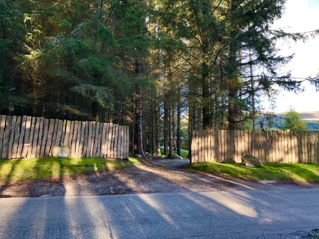a wooden fence next to a road with trees at Belforte House Holiday Home in Inverness