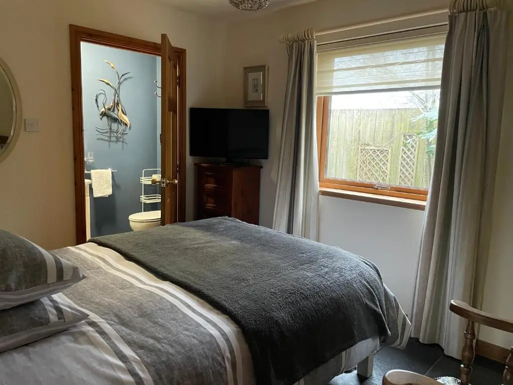 a bedroom with a bed and a window and a television at Old Mills Garden in Elgin