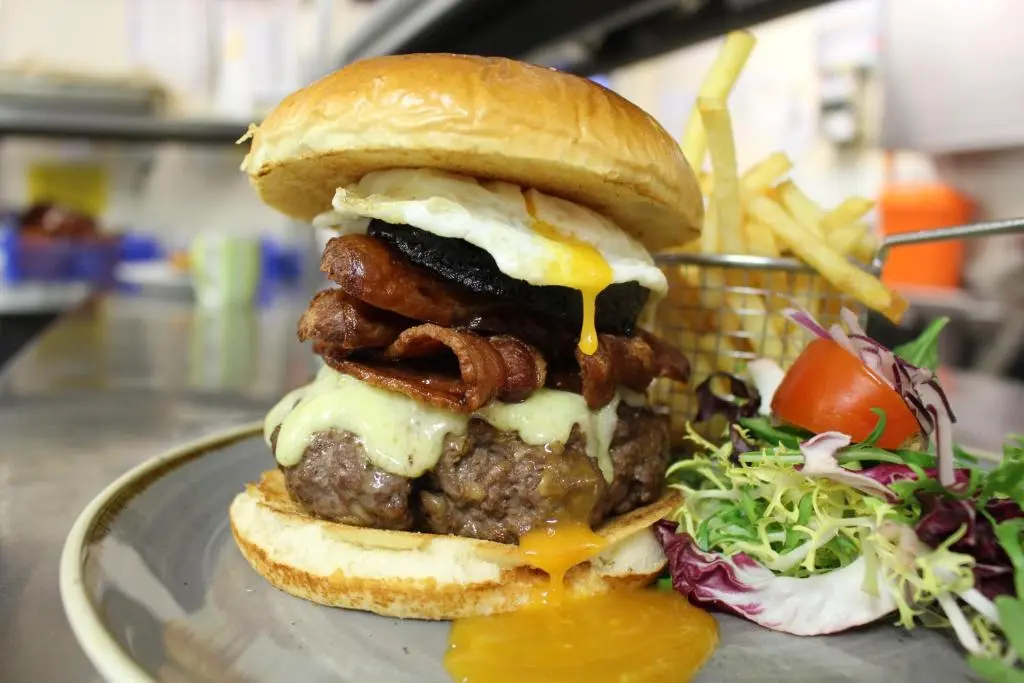 a cheeseburger with meatballs and cheese on a bun with fries at Newmachar Hotel in Newmachar