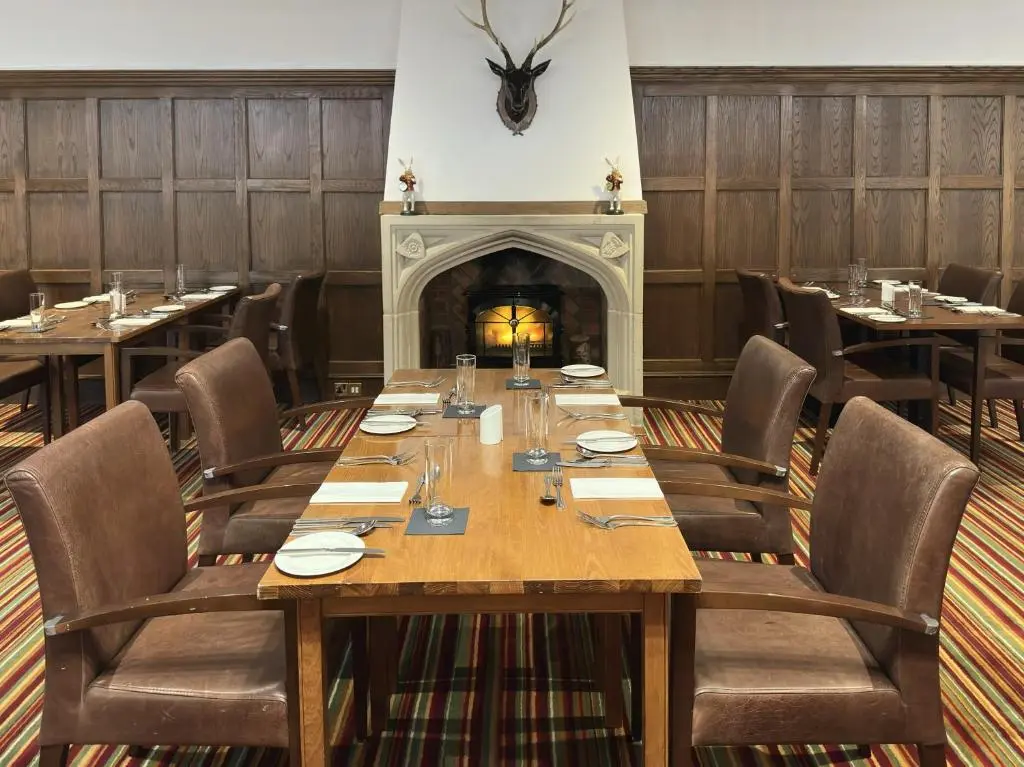 a dining room with a table and a fireplace at The Aberdeen Dyce Hotel in Dyce