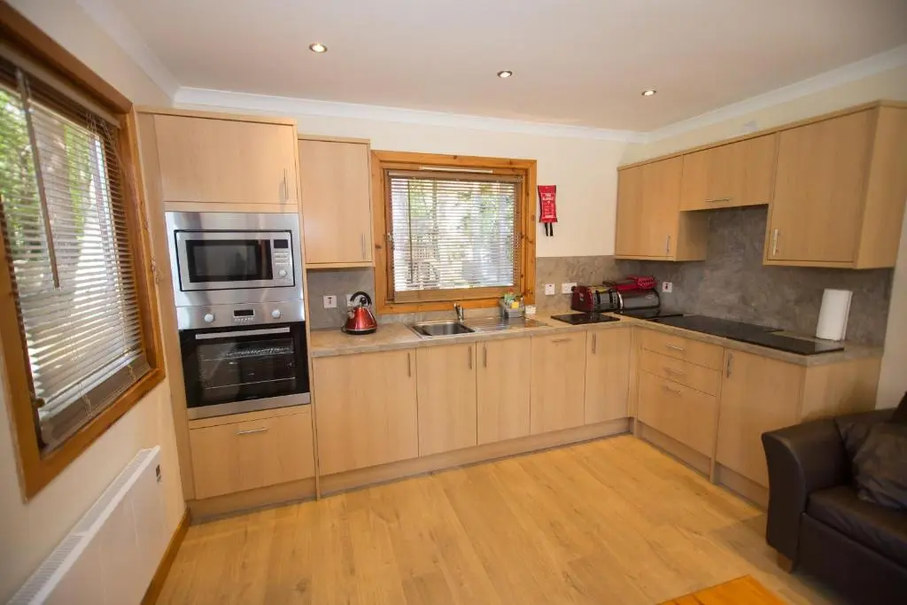 a kitchen with wooden cabinets and a stove top oven at Invercauld Lodges in Ballater