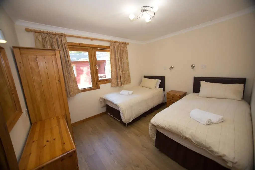 a bedroom with two beds and a window at Invercauld Lodges in Ballater