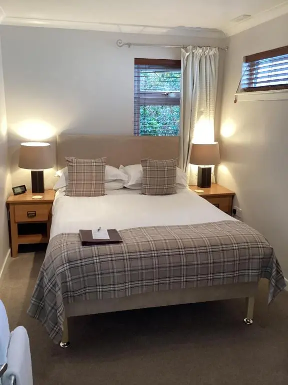 a bedroom with a bed and two lamps and a window at Furan GuestHouse in Inverness