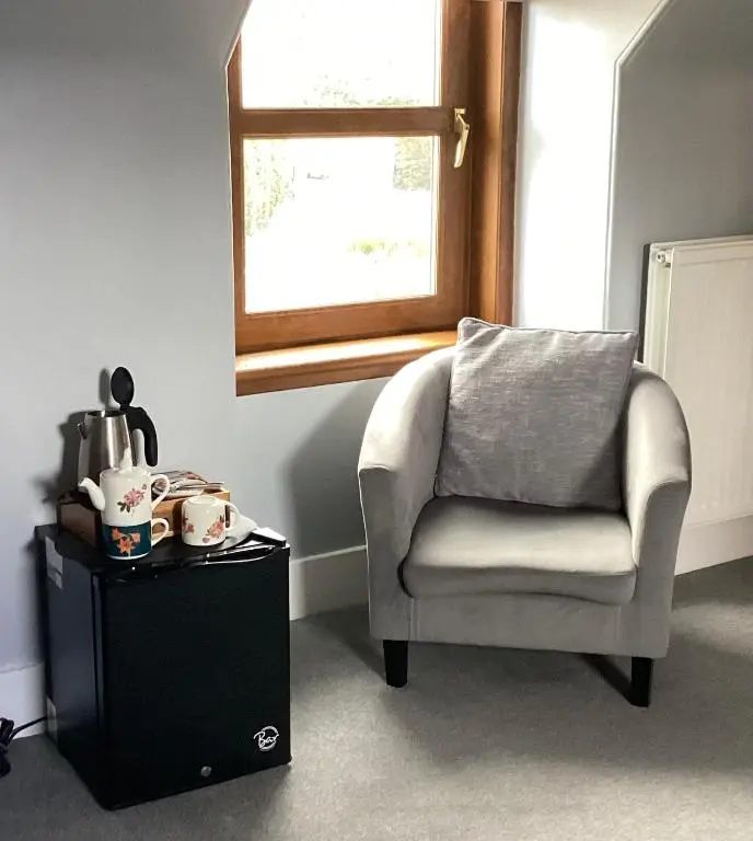 a chair sitting under a window next to a table at Furan GuestHouse in Inverness