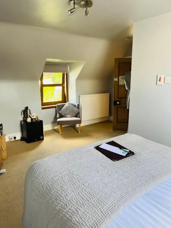 a bedroom with a bed and a chair and a window at Furan GuestHouse in Inverness