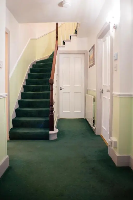 a hallway with a staircase with green carpet at Dunvegan Bed & Breakfast in Dufftown