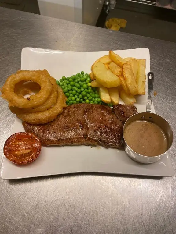 a plate of food with meat and chips and onion rings at The Albert Inn in Nairn