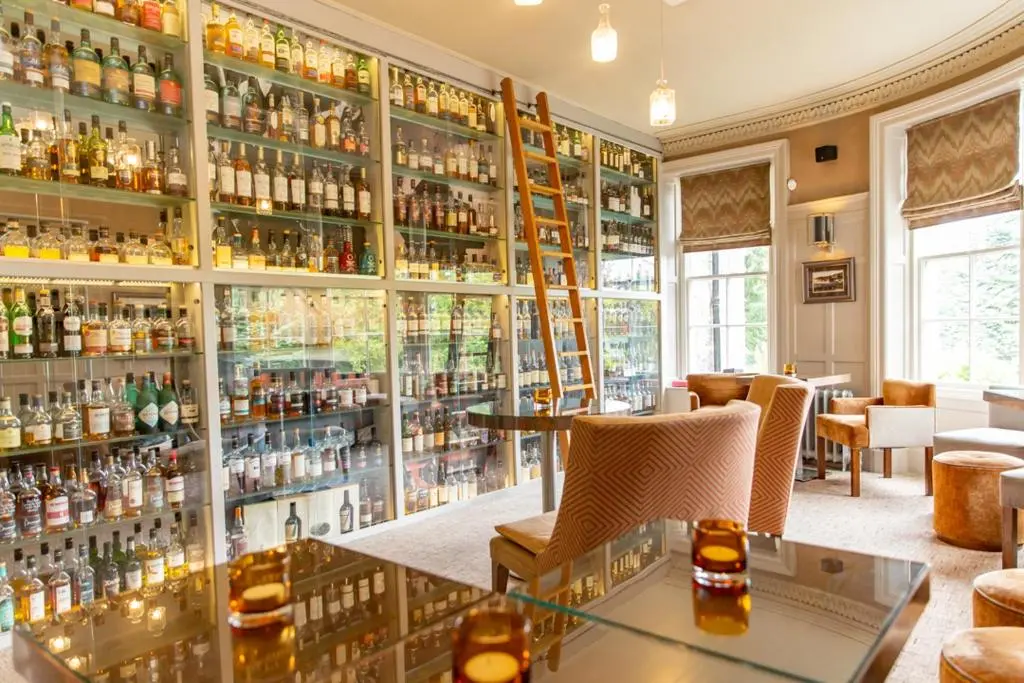 a bar with shelves filled with bottles of alcohol at The Dowans Hotel of Speyside in Aberlour