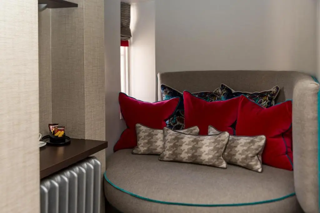 a couch with red pillows on it in a room at The Dowans Hotel of Speyside in Aberlour