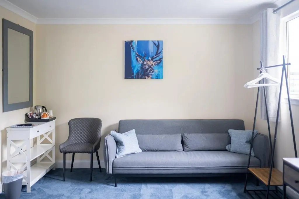 a living room with a couch and a chair at Loch Ness Clansman Hotel in Drumnadrochit