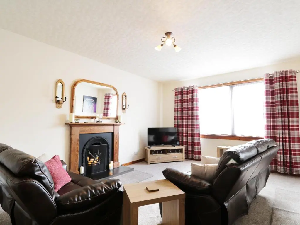 a living room with two leather chairs and a fireplace at Dalnahaven in Grantown on Spey