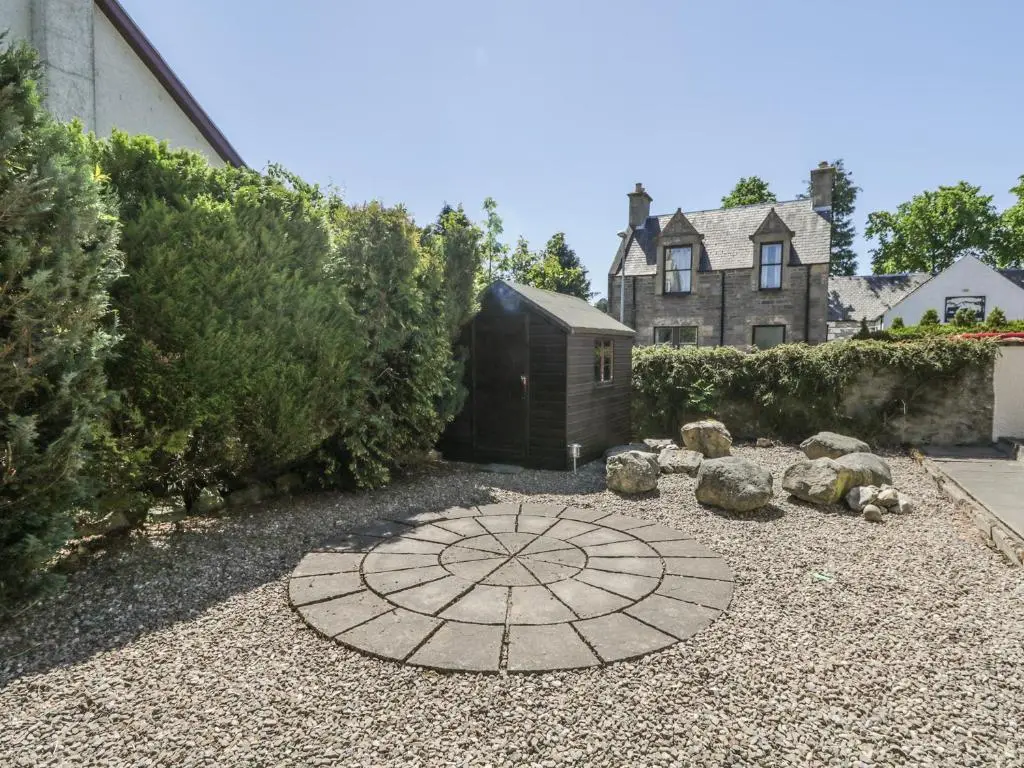 a garden with a stone circle in front of a house at Dalnahaven in Grantown on Spey