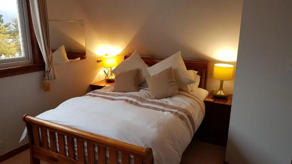 a bedroom with a large white bed with two lamps at Lochview Guest House in Ullapool