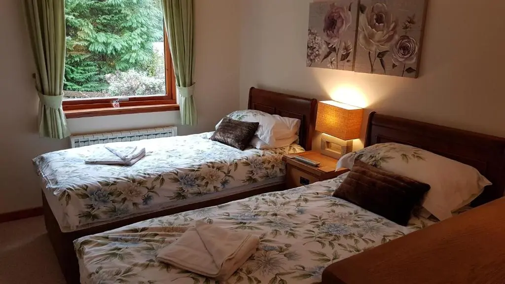 two beds in a small room with a window at Lochview Guest House in Ullapool
