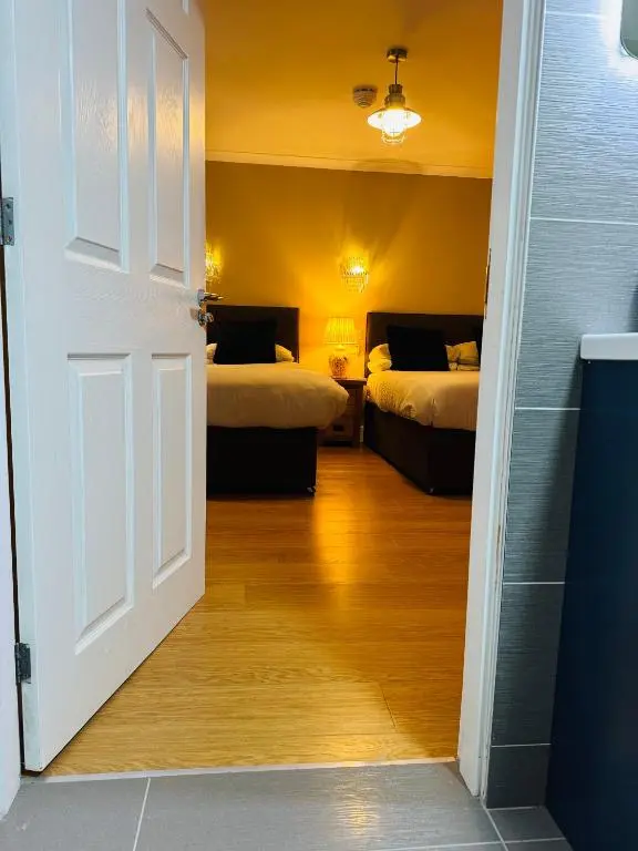 a room with two beds and an open door at The Milton Accommodation in Elgin