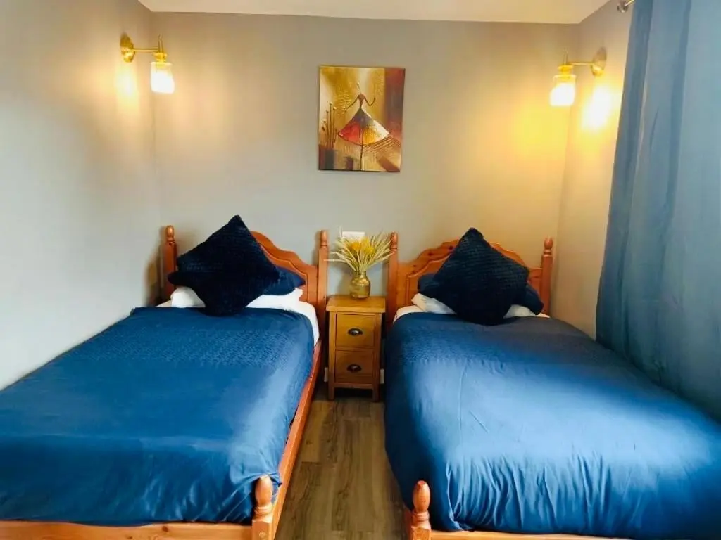 two beds in a room with blue sheets at The Milton Accommodation in Elgin