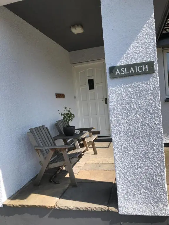 aouple of benches and a table in front of a building at Aslaich in Drumnadrochit