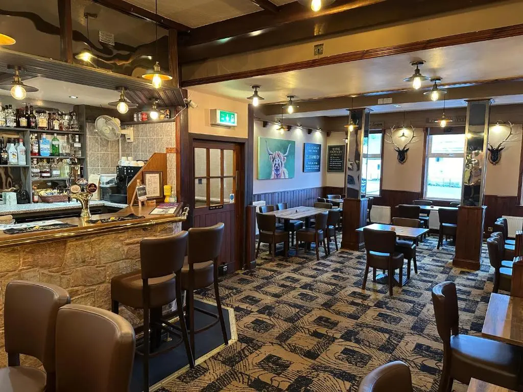 a restaurant with a bar and tables and chairs at The Glen Hotel Newtonmore - Rooms, bar & restaurant in Newtonmore