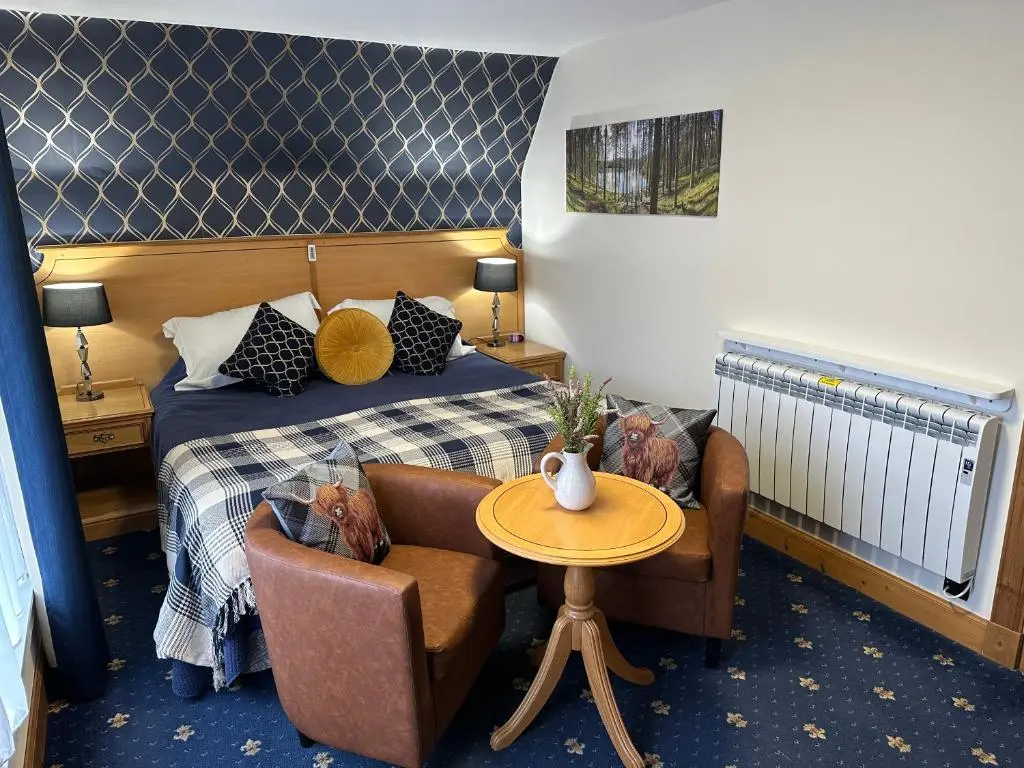 a hotel room with a bed and a table and chairs at The Glen Hotel Newtonmore - Rooms, bar & restaurant in Newtonmore