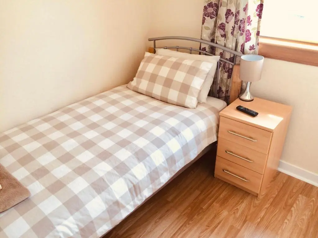 a small bedroom with a bed and a night stand at Invermac House in Inverness