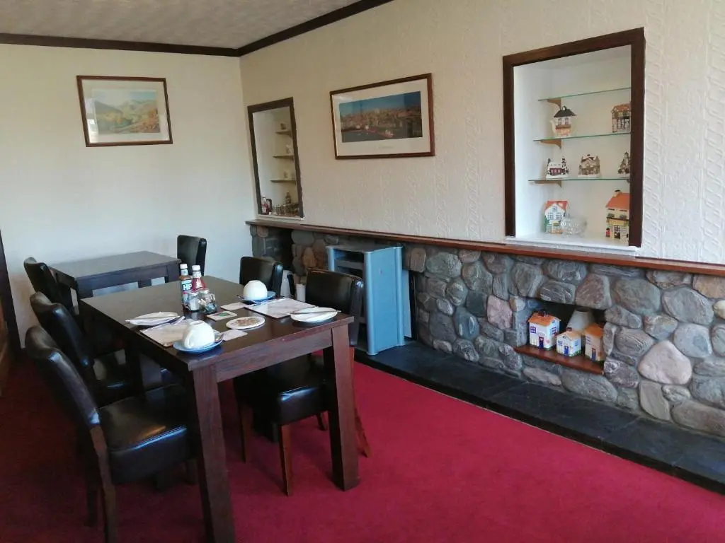 a dining room with a table and a fireplace at Celicall in Ballater