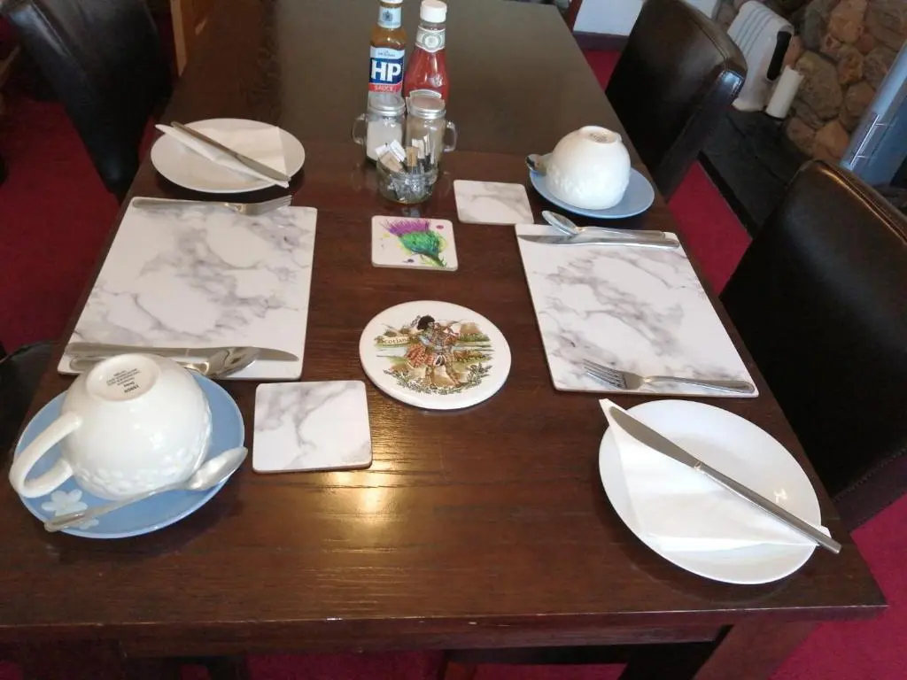 a wooden table with plates and utensils on it at Celicall in Ballater