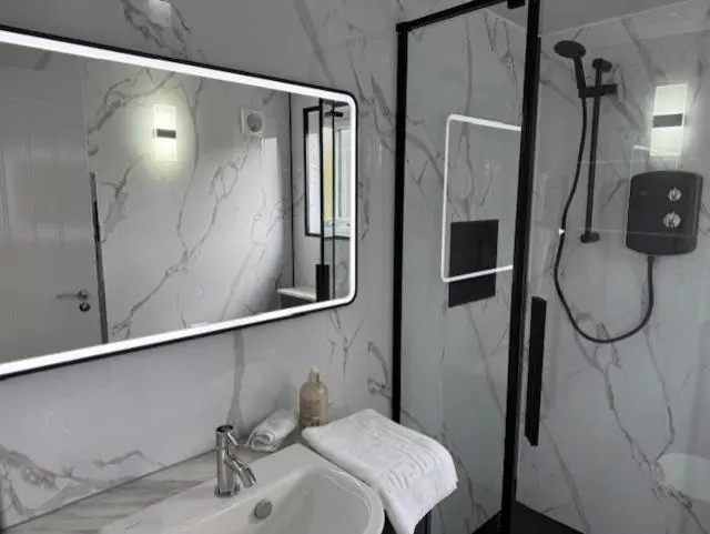 a bathroom with a sink and a mirror and a shower at Ledgowan Bunkhouse in Achnasheen