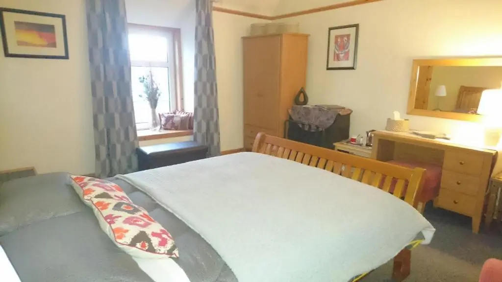 a bedroom with a bed and a dresser and a mirror at Kindale House in Helmsdale
