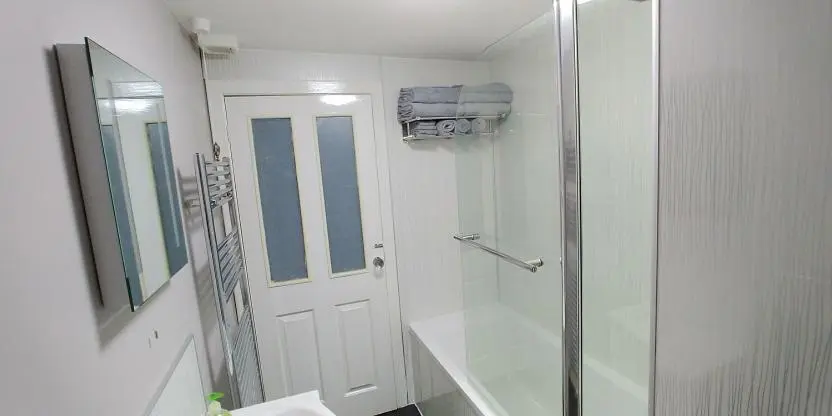 a bathroom with a shower and a glass door at Brae Cottage, Inverness in Inverness