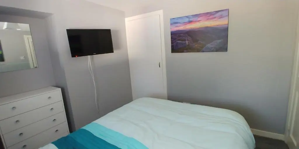 a bedroom with a bed and a tv on the wall at Brae Cottage, Inverness in Inverness