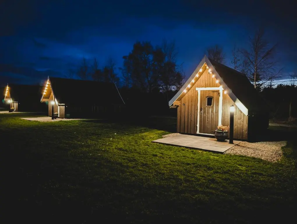 a small shed with lights on the side of a yard at night at Macbeth's Hillock in Forres