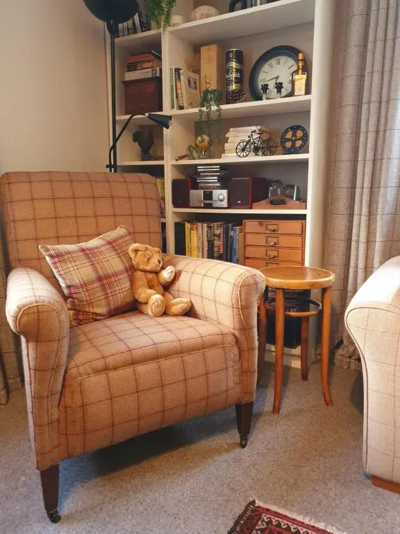 a teddy bear sitting on a chair in a living room at Clachan Farmhouse B & B in Ullapool