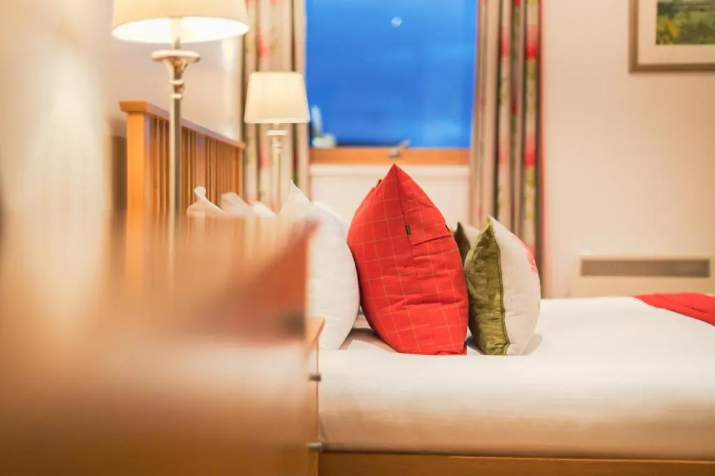 a bedroom with a bed with red and green pillows at Highland Apartments by Mansley in Inverness