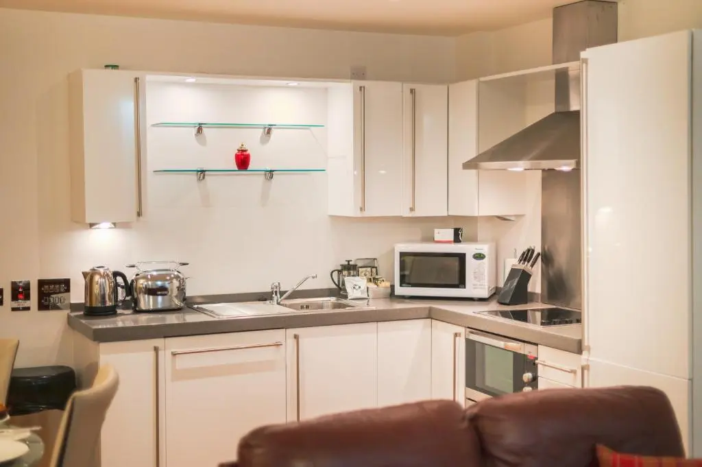 a kitchen with white cabinets and a microwave at Highland Apartments by Mansley in Inverness