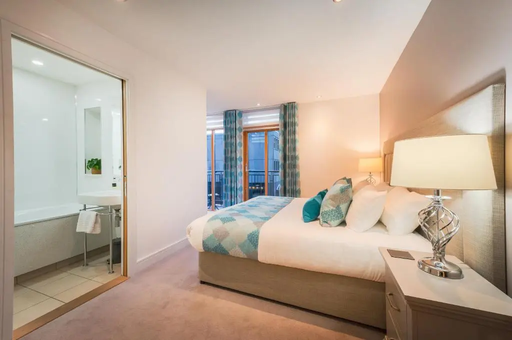 a bedroom with a bed and a bathroom with a mirror at Highland Apartments by Mansley in Inverness