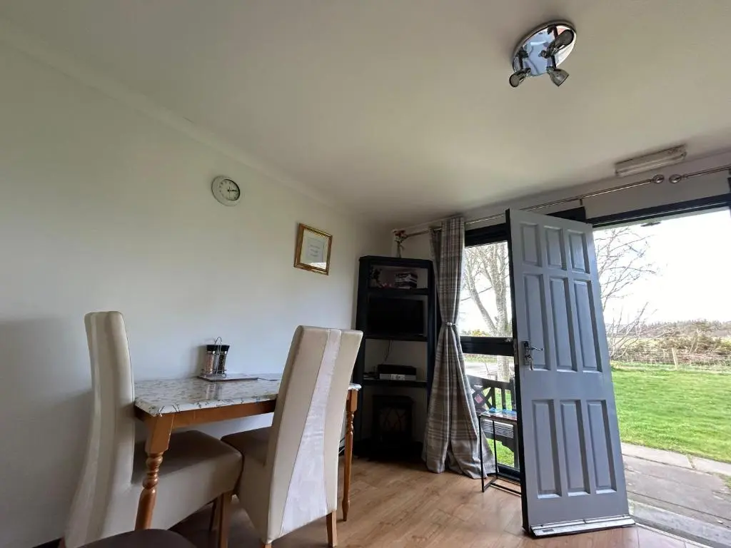 a dining room with a table and chairs and a door at Kilcoy Chalets in Muir of Ord