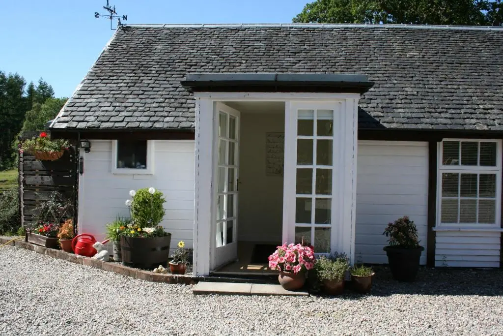 a small white shed with potted plants in front of it at Ardgarry Farm in Invergarry