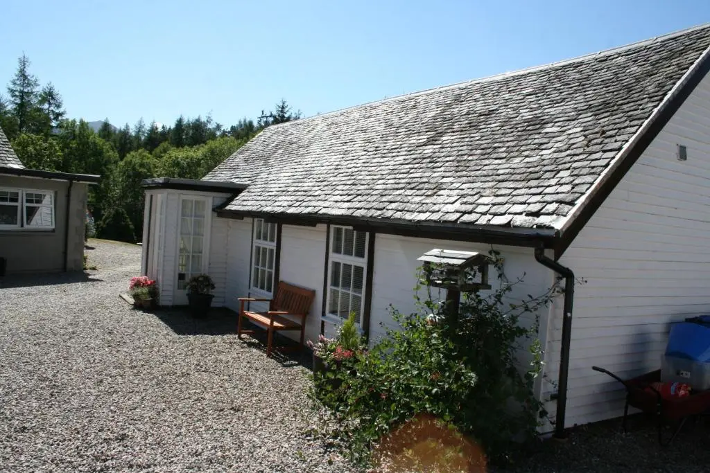 a small white house with a bench in front of it at Ardgarry Farm in Invergarry