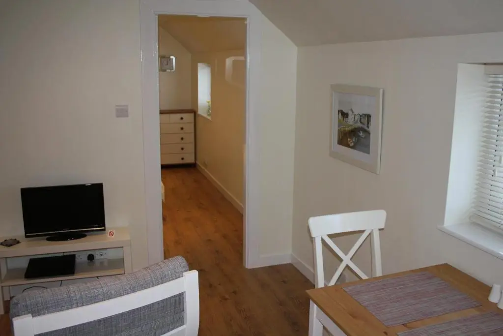 a living room with a television and a table with a chair at Ardgarry Farm in Invergarry