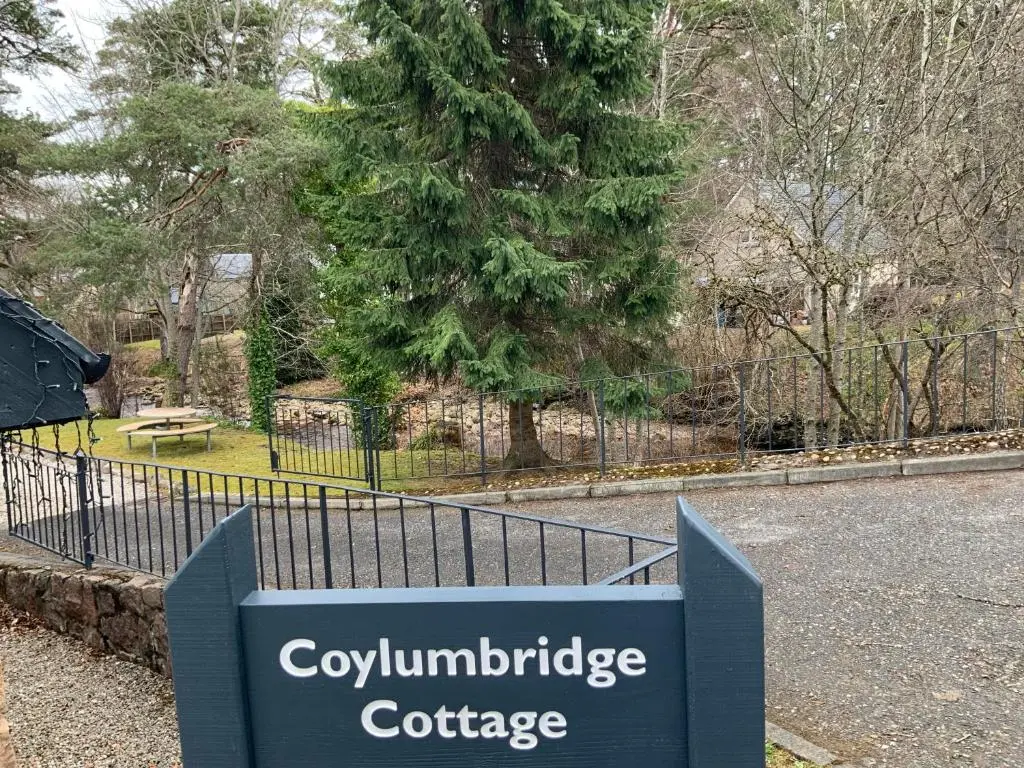 a sign in front of a fence in a park at Coylumbridge Cottage in Aviemore