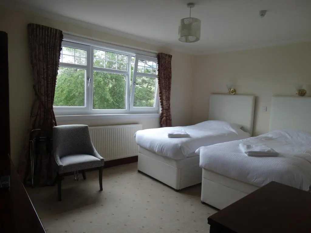 a room with two beds and a chair and a window at Laggan Hotel in Laggan